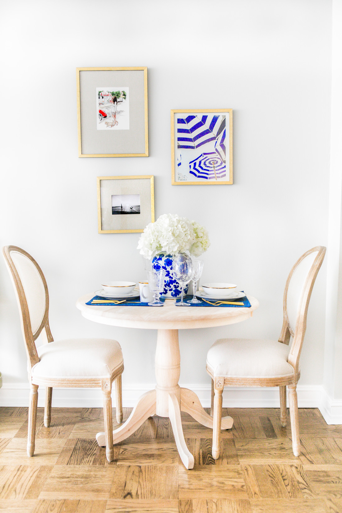 Lauren-Nelson-At-Home-Natural-Wood-Round-Dinning-Table-White-French-Chairs-West-Elm-Gold-Frame-Gallery-Wall